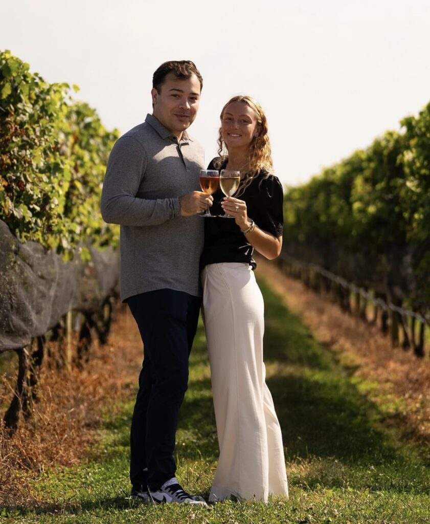 COUPLE POSING WITH WINE GLASSES TOASTING THEIR ENGAGEMENT