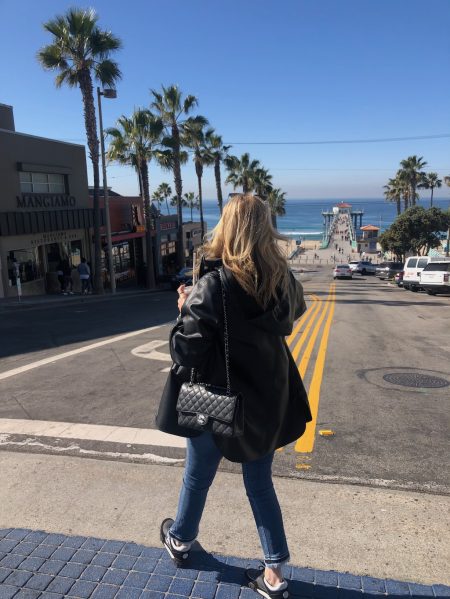 BACK SIDE OF WOMAN ON STREET OVERLOOKING MANHATTAN BEACH PIER AND OCEAN